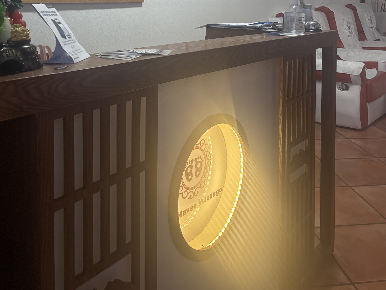 The reception desk at Gold Haven Massage with its lit gold roundel sign