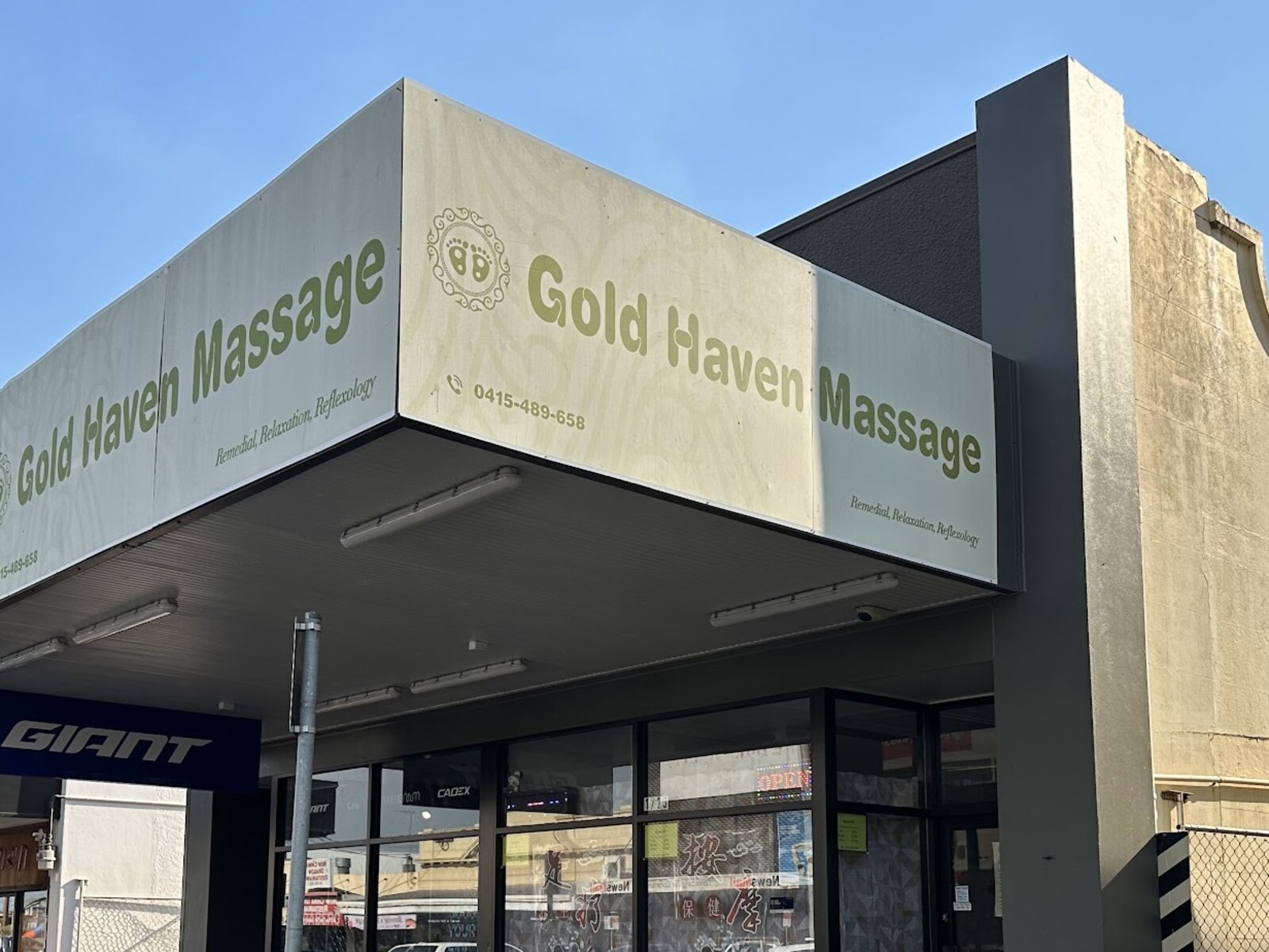 The illuminated Gold Haven Massage sign above the shopfront on Targo Street